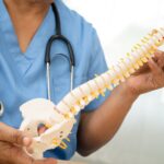 Asian doctor holding spinal nerve and bone model, Lumbar spine displaced herniated disc fragment